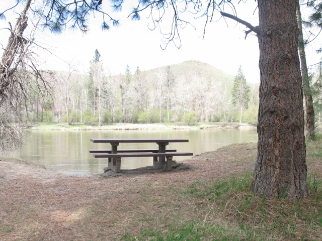 picture showing There are two picnic tables next to the river. Neither have wheelchair seating.